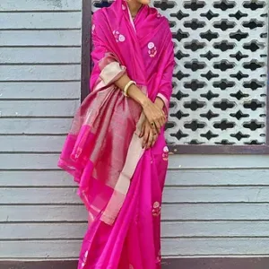 Woman wearing a bright pink pure silk Chanderi saree featuring delicate white floral butta motifs and a silver zari pallu with border highlights, styled with minimal jewelry.